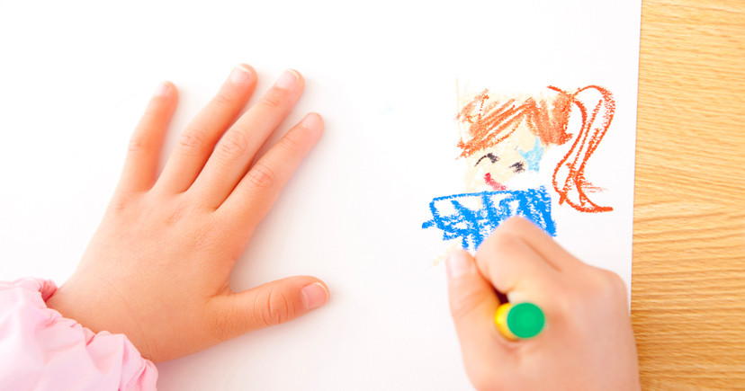 クレヨンで絵を描く幼稚園児の手元