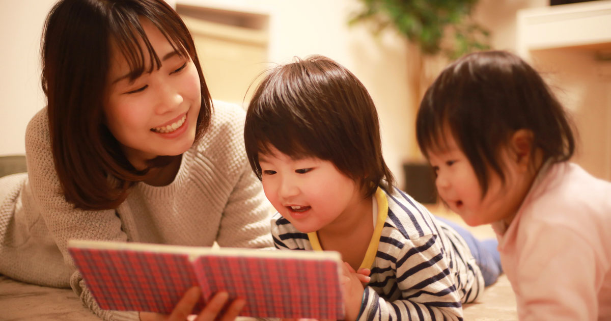 子どもに本の読み聞かせをしている女性の画像