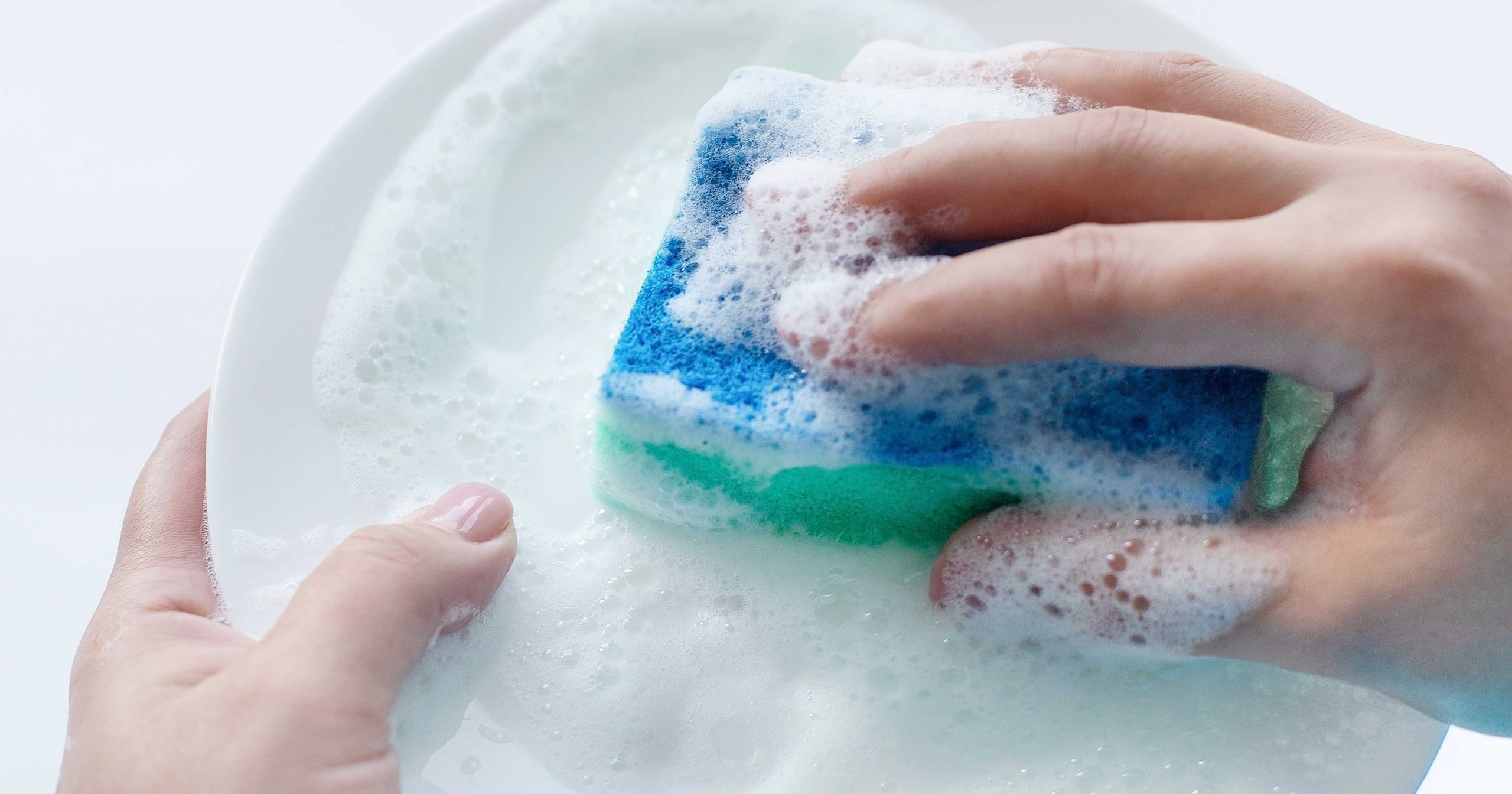 青いスポンジで食器を洗っている写真