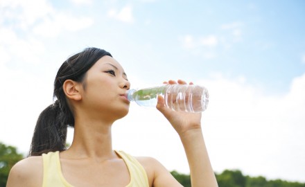 ペットボトルで水を飲む女性の写真
