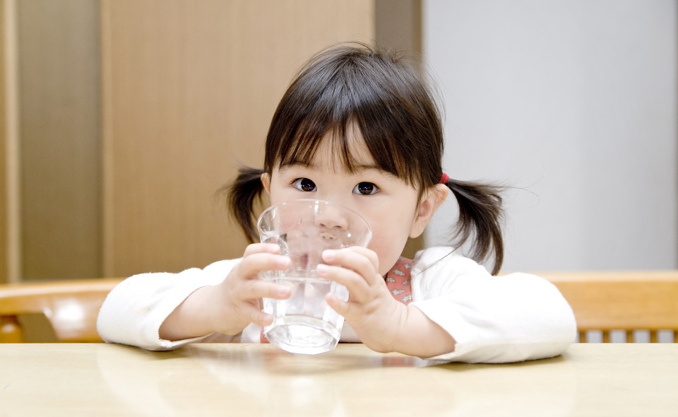 コップで水を飲む女の子の写真