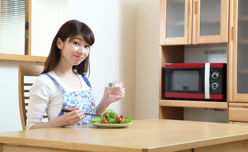 食卓で水を飲む女性の写真